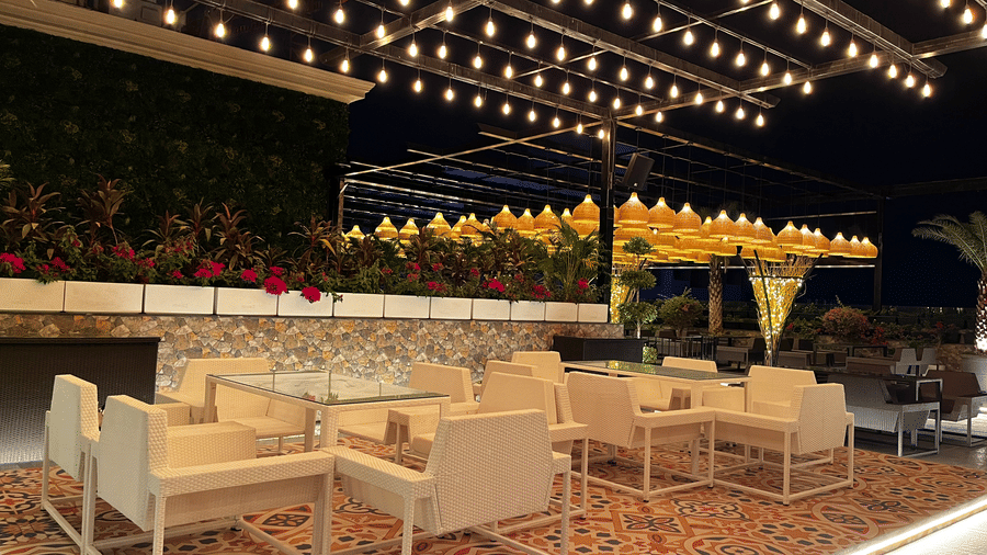 Rooftop seating at The Beatle Hotel, Powai. White furniture, string lights, a colorful patterned rug, and a vertical garden wall.