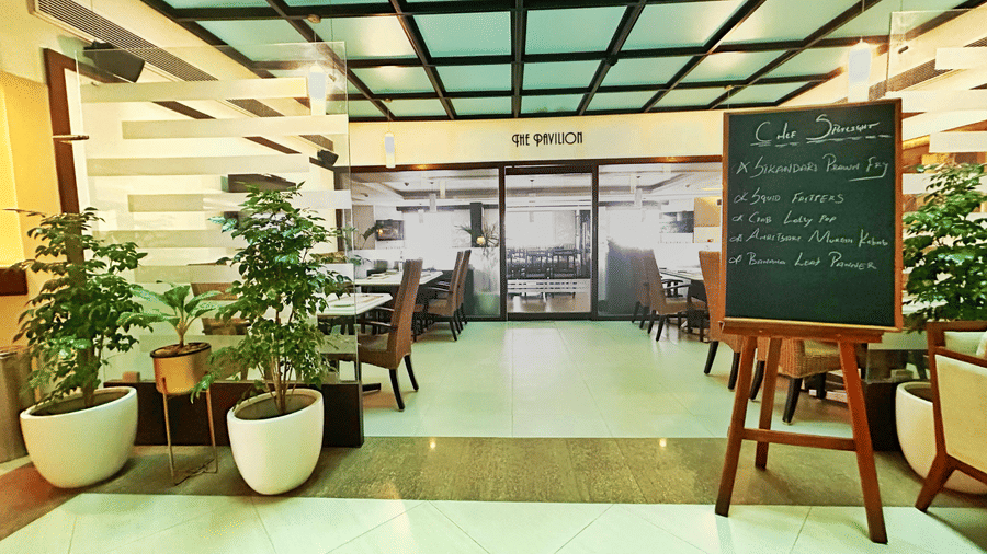 Entrance to the hotel restaurant featuring modern interiors, indoor plants, and seating arrangements.