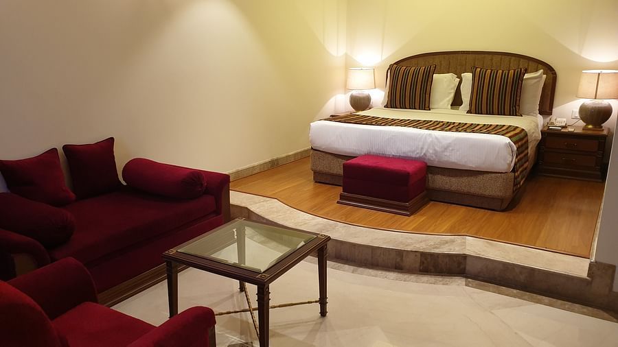 An image of Luxury Suite with king size bed and a seating area with sofa and a centre table  - The Suryaa New Delhi