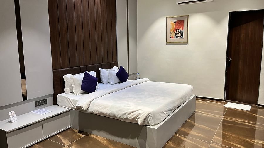 A king bed next to a side table in super deluxe room - VITS Jamnagar, Mithoi