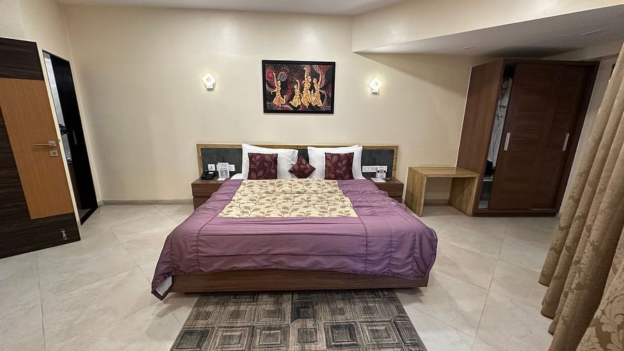 Double bed room with bedside table, storage unit, and ceiling lights at VITS Kamats Resort, Silvassa