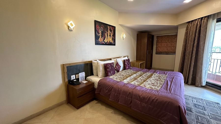Doule bed room with bed side table, storage unit, and ceiling-to-floor windows at VITS Kamats Resort, Silvassa
