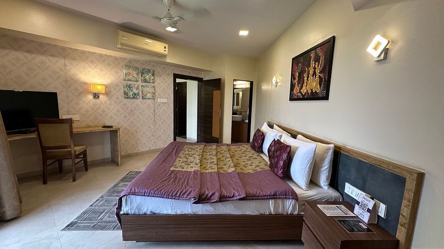 Double bedroom with bedside table, work stations, and wall-mounted TV at VITS Kamats Resort, Silvassa