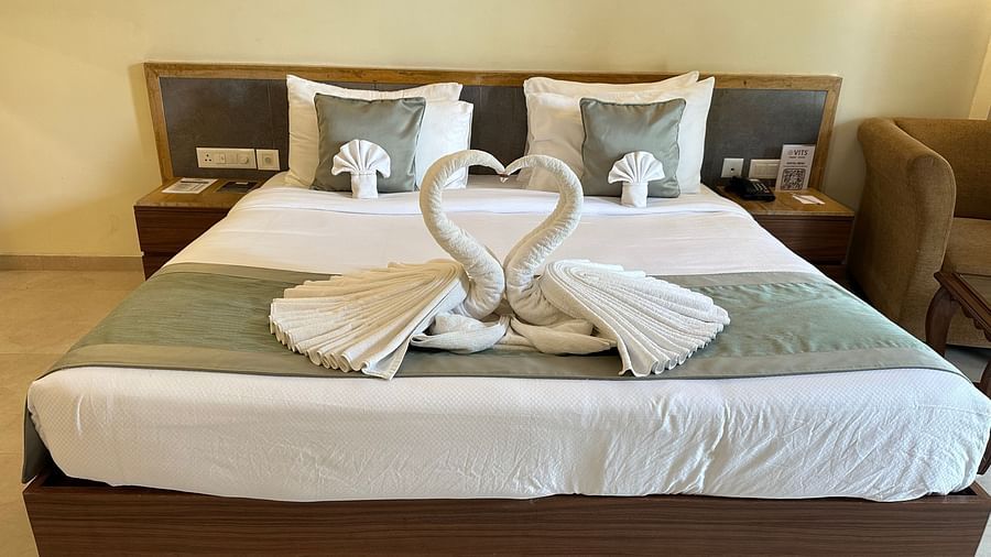 11zon IMG 5094Double bed room with a swan made of white towel above it, bedside table, and a Sofa by the corner at VITS Kamats Resort, Silvassa