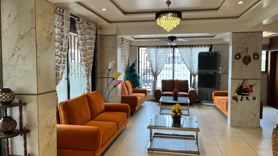 An overview of the lobby area  of VITS Select Kharadi, Pune - The best hotel near EON IT Park, Pune, with orange couches placed in front of coffee tables and a chandelier hung on the roof at VITS Select Kharadi, Pune.