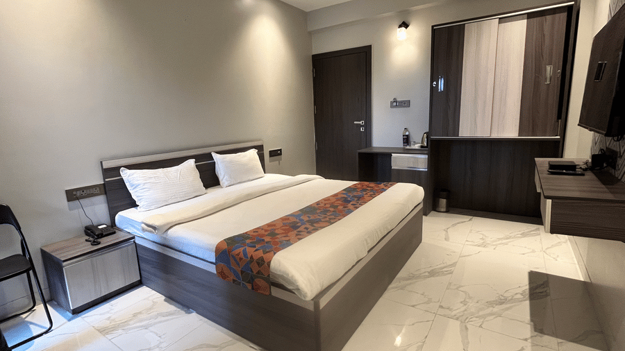 An overview of Super Deluxe Rooms in Pune with a large bed with a head board, a night stand, a television and a wardrobe to the side at VITS Select Kharadi, Pune.