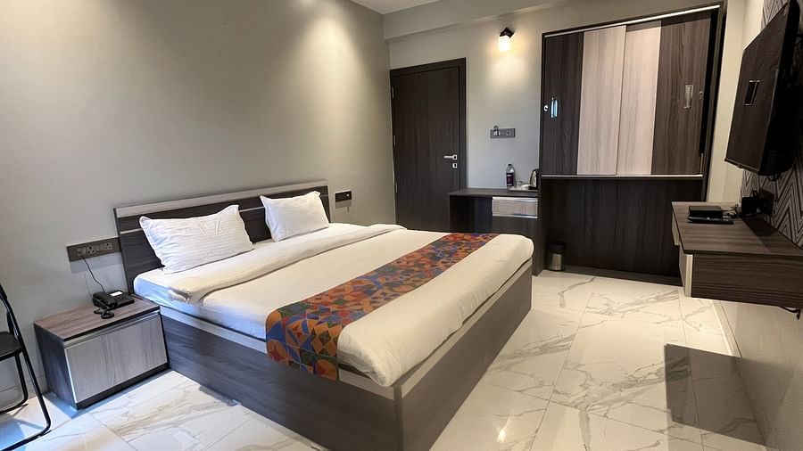 A hotel bedroom with a large bed with a head board, a night stand, a television and a cup board to the side at VITS Select Kharadi, Pune.