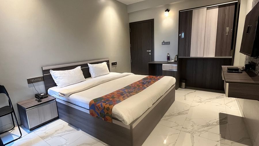 A hotel bedroom with a large bed with a head board, a night stand, a television and a cup board to the side at VITS Select Kharadi, Pune.