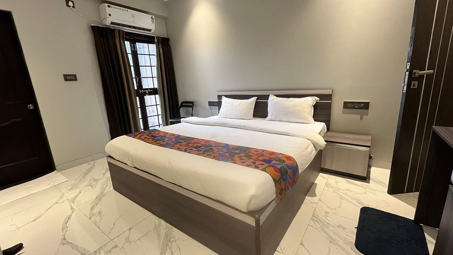 A hotel room with a large bed placed under ambient yellow lights brightening the room at VITS Select Kharadi, Pune.