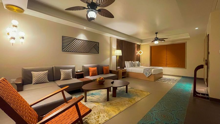 A stretchy suite with a living area with sofas, coffee tables and a chair. Also, a large bedding with pillows and coverlets on the view.