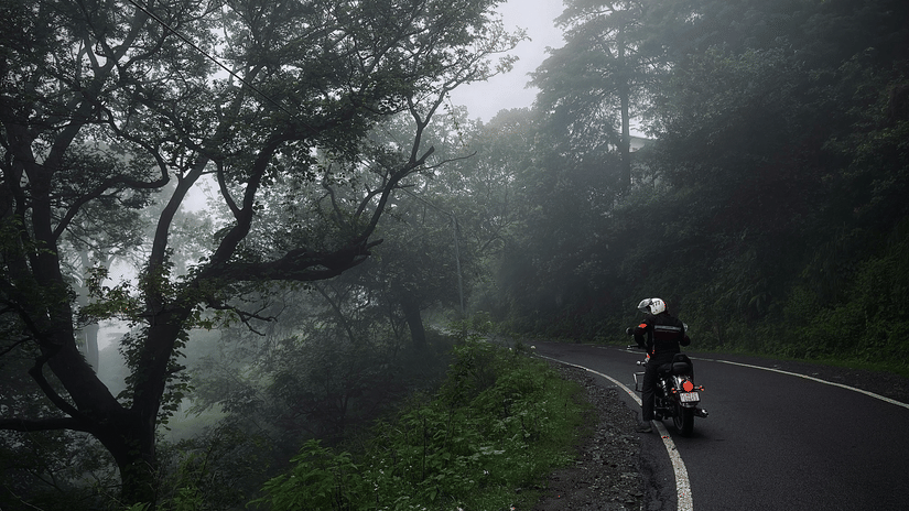 A person on a motorcycle rides along a winding road through a foggy, forested area | Himavad Gopalaswamy Temple history
