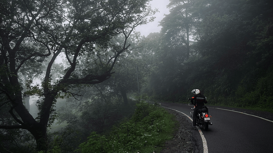 A person on a motorcycle rides along a winding road through a foggy, forested area | Himavad Gopalaswamy Temple history