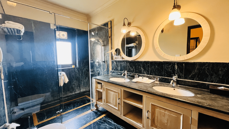 Well-appointed bathroom in Juna Mahal deluxe room with dual mirrors, wooden vanity and modern fittings in a heritage styled setting