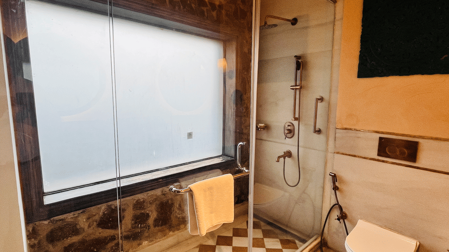 Premium Deluxe Room bathroom at Juna Mahal, Ranthambore with glass shower, modern fittings, natural light and elegant tiled flooring for a refreshing stay