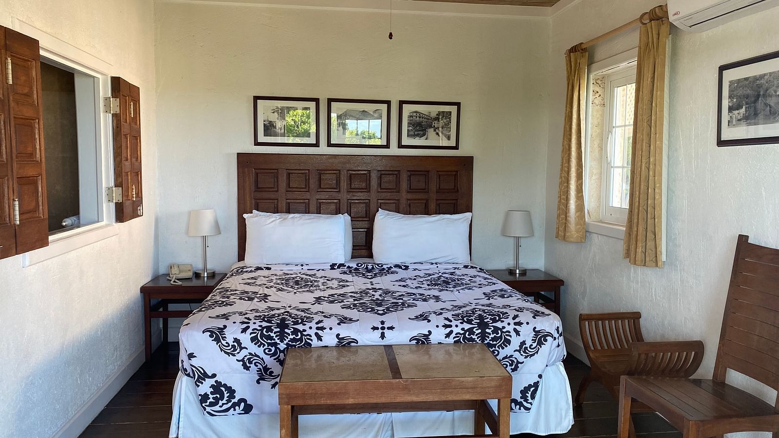 Bedroom with a large bed, ceiling fan, table, chair, and framed art on the wall | A Stone's Throw Away
