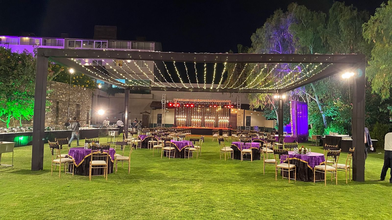 Outdoor event with lit tents and tables at night.