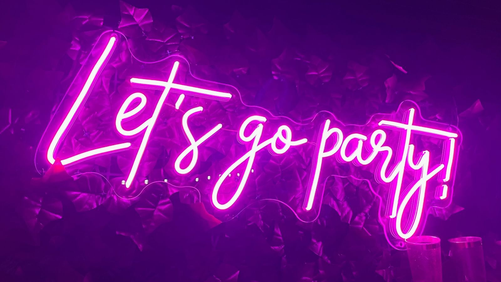 A neon light sign outside a club with the words let's go party!