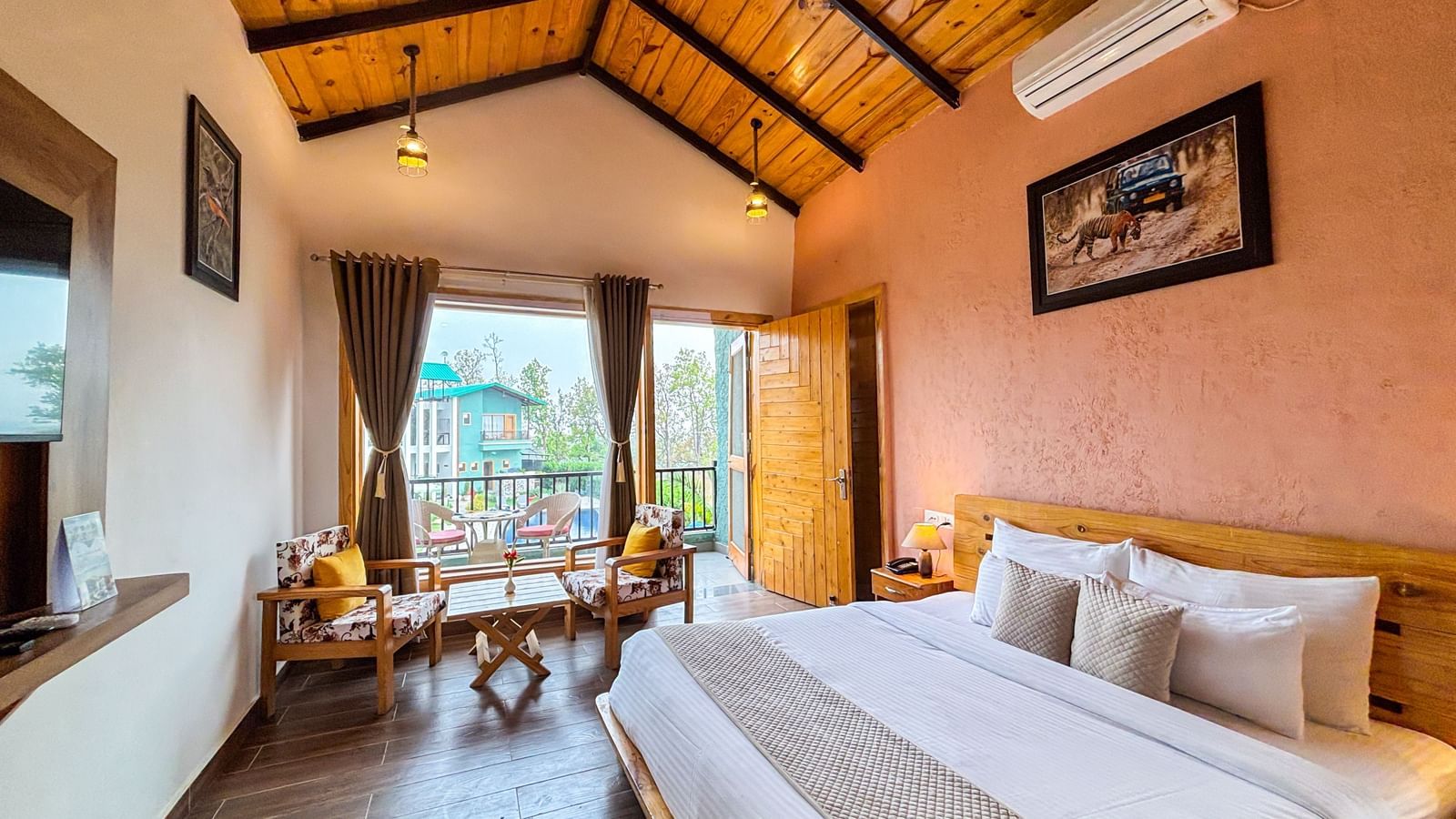 Spacious room with wooden ceiling, king size bed, and balcony access at Corbett Nirvana Resort