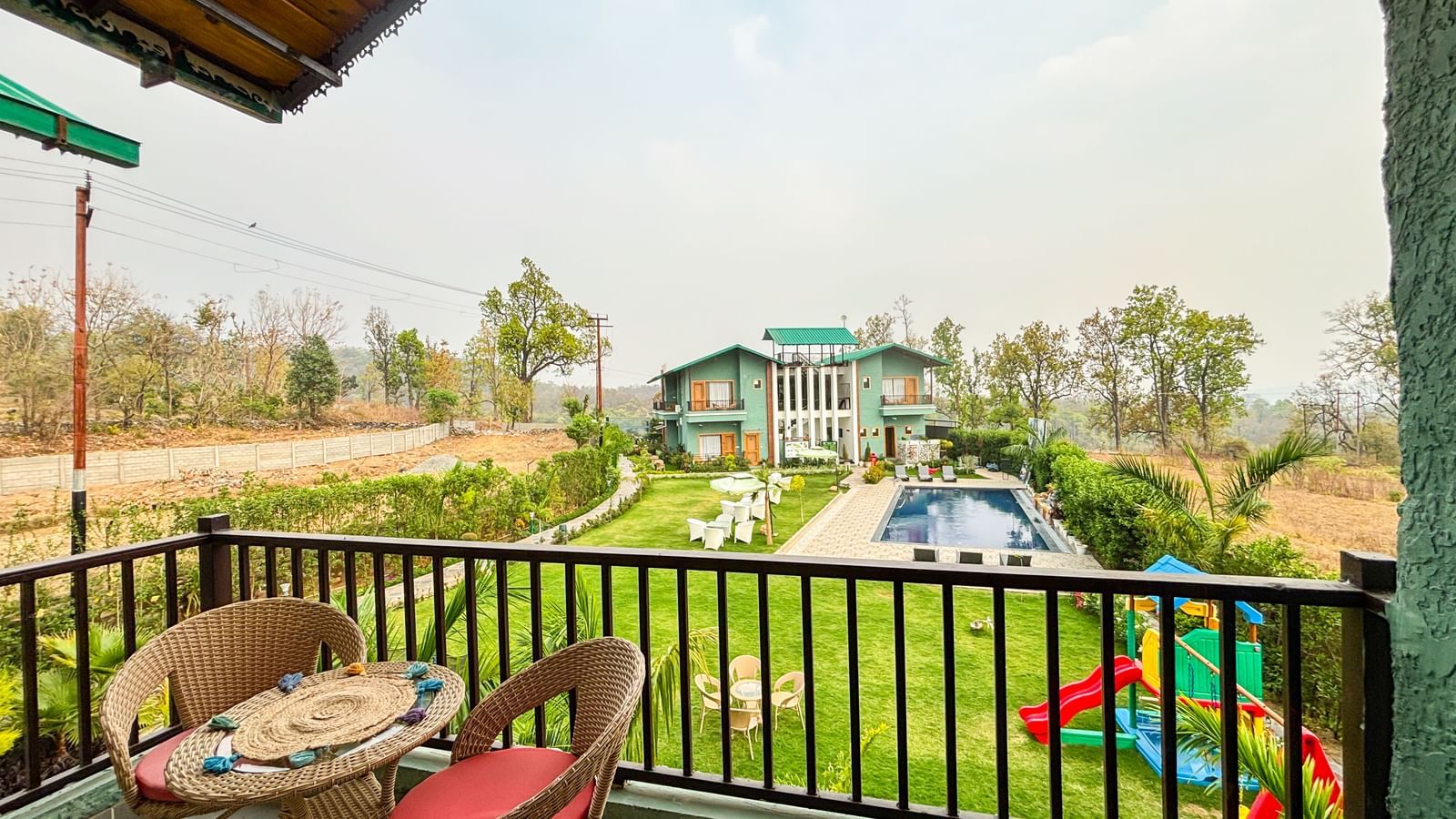 A cosy coffee table kept on a balcony of Corbett Nirvana Resort overlooking the lawn area.