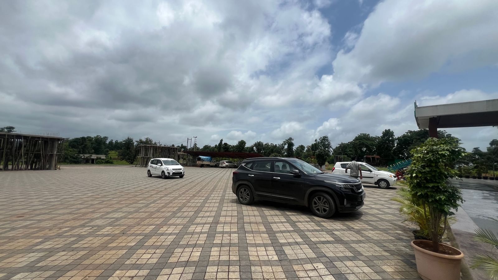Outdoor parking area of Daksh The Valley Resort, Saputara, seen on a cloudy day, with few cars standing in the tiled ground.