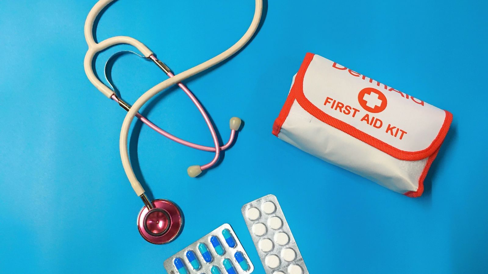 Medical supplies including a stethoscope, first aid kit, and medication blister packs on a blue background | Diamond Parks, Pune