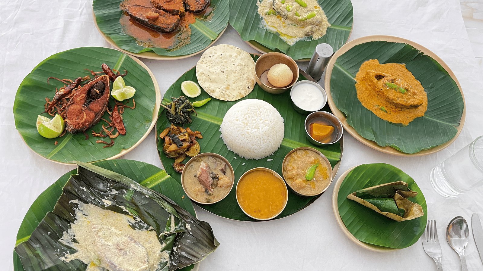 A grand thali platter with multiple vegetarian and fish dishes plated on a banana leaf at Dip Holidays