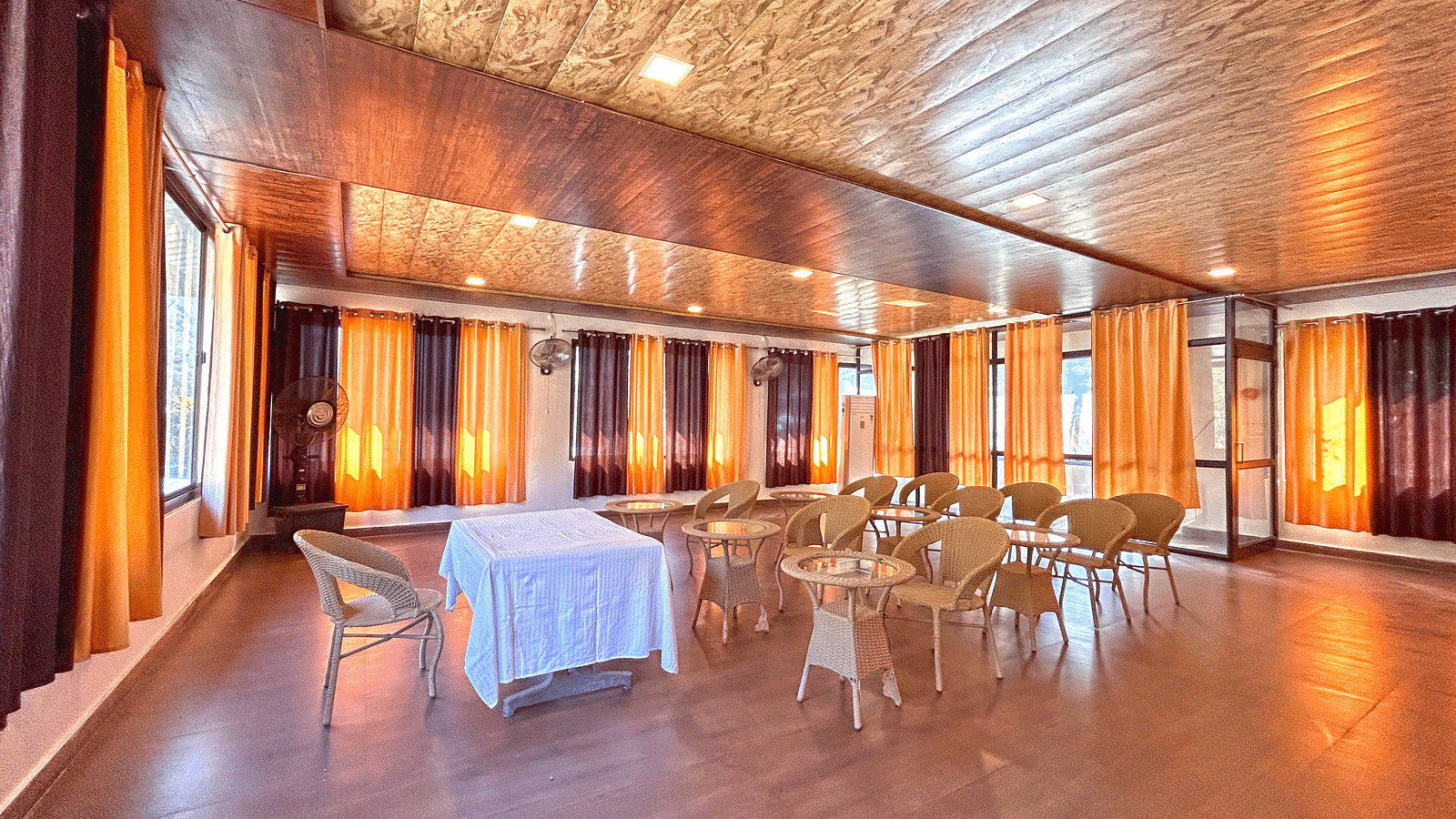 A conference hall with ambient lighting and chairs facing a white table at DLS MJ River Resort, Rishikesh.