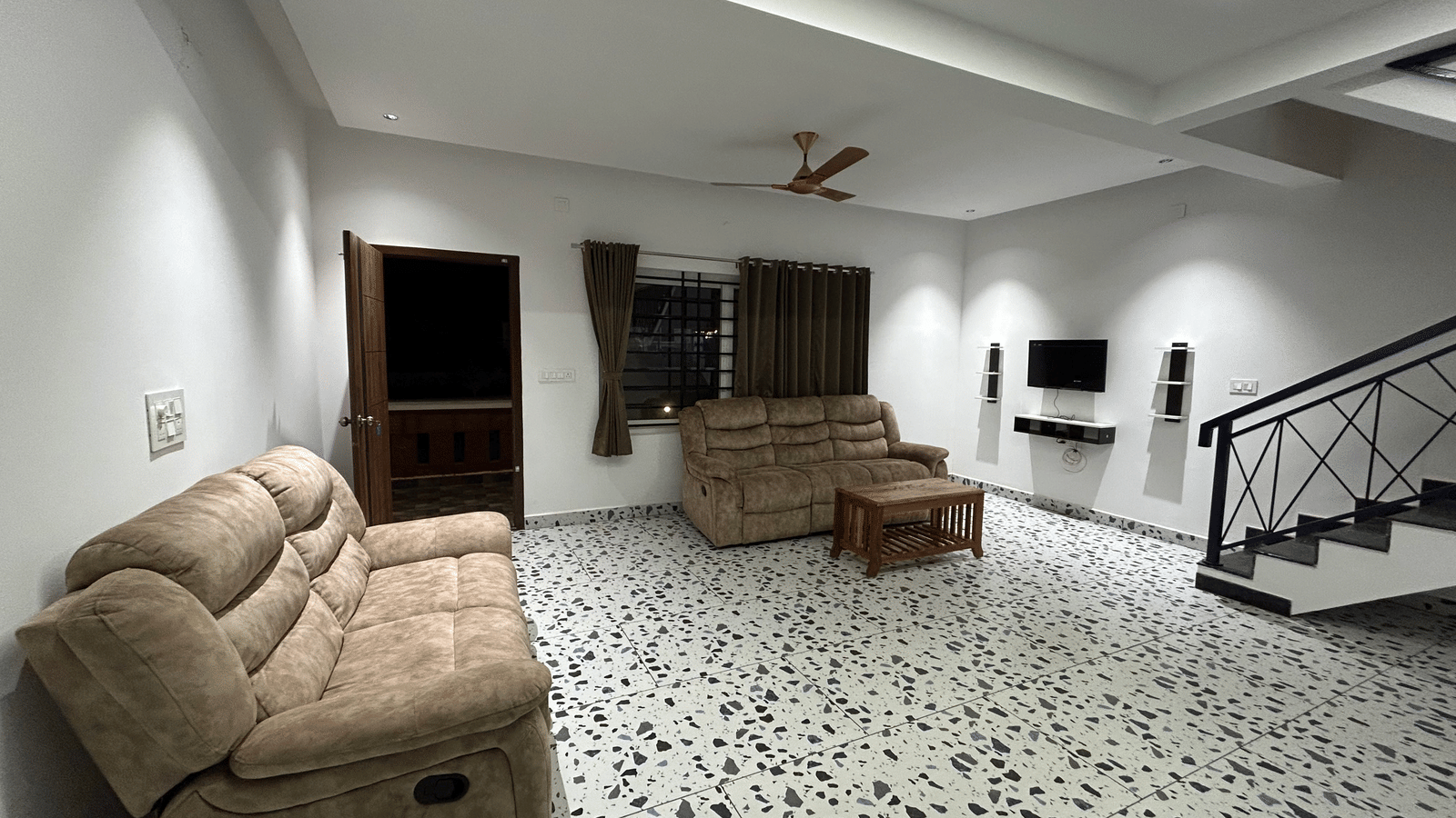 Hatti Eden Coorg | A living room with sofas, a fan, a door, and stairs.
