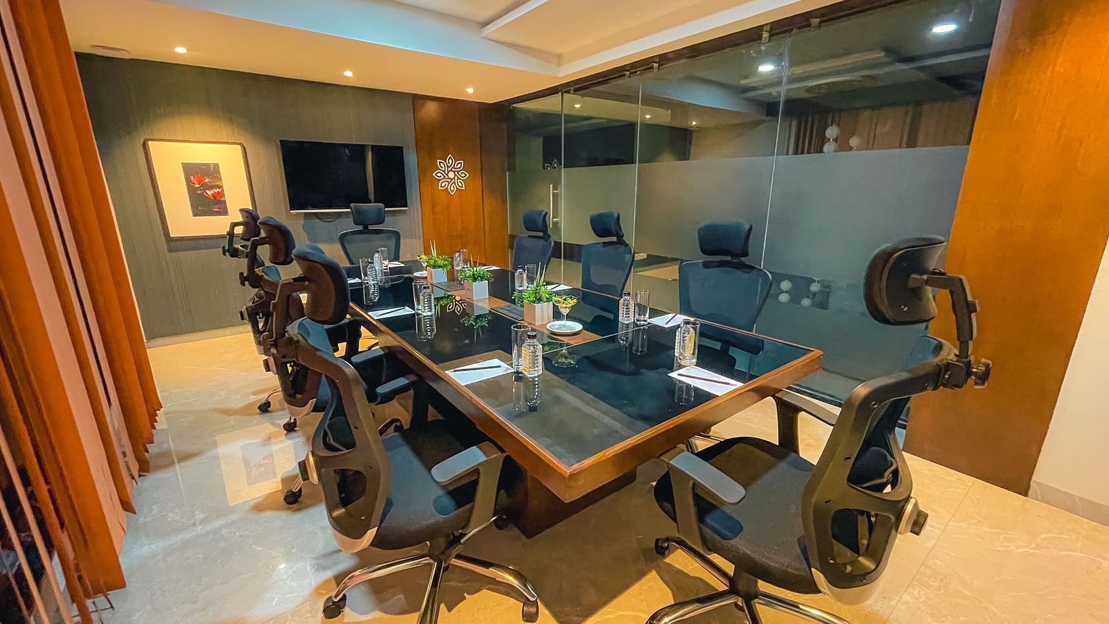 a room with a rectangular table surrounded by chairs and a mounted television - Jardin Hotels