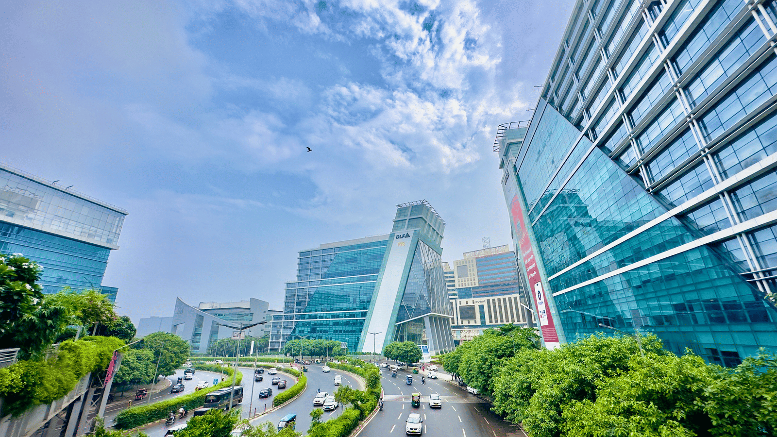 An overview of DLF Cyber City with buildings and trees and clouds in the background