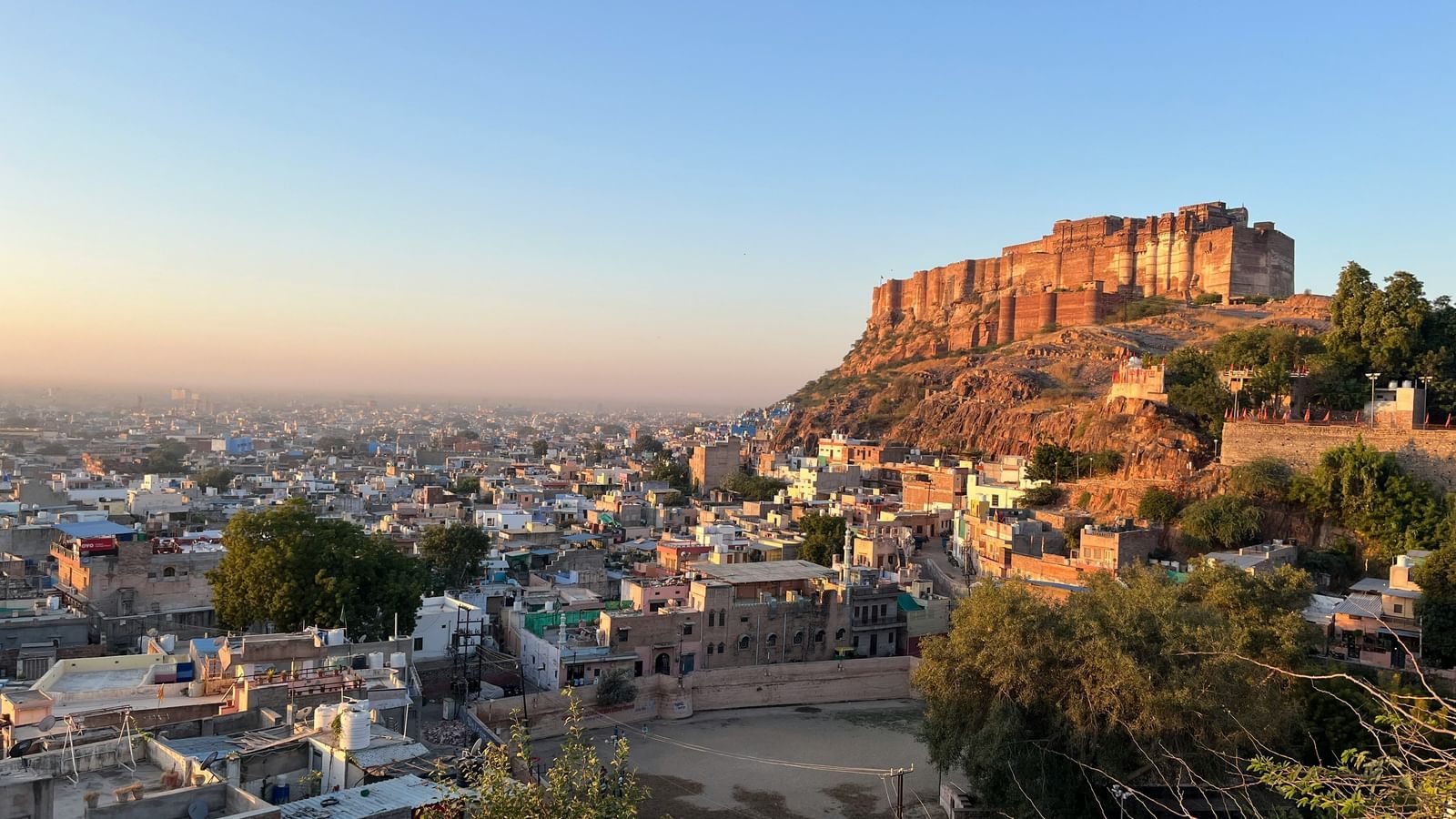 A wide angle view of a city with a fort perched on top of  a hill