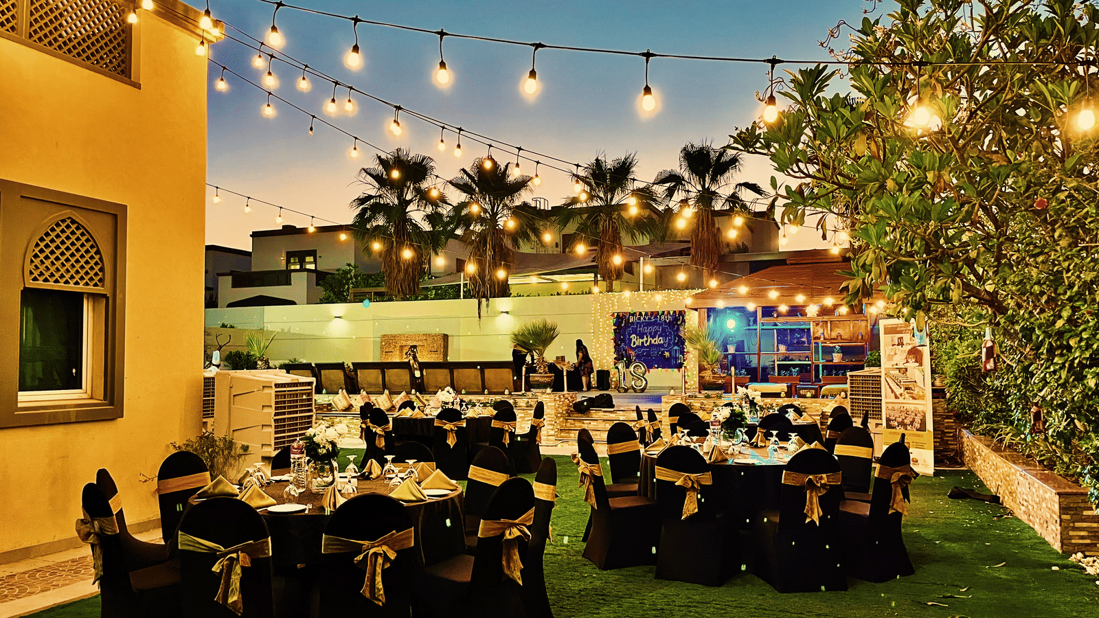 Outdoor dining area setup with tables and string lights at Marco Polo Hotel.