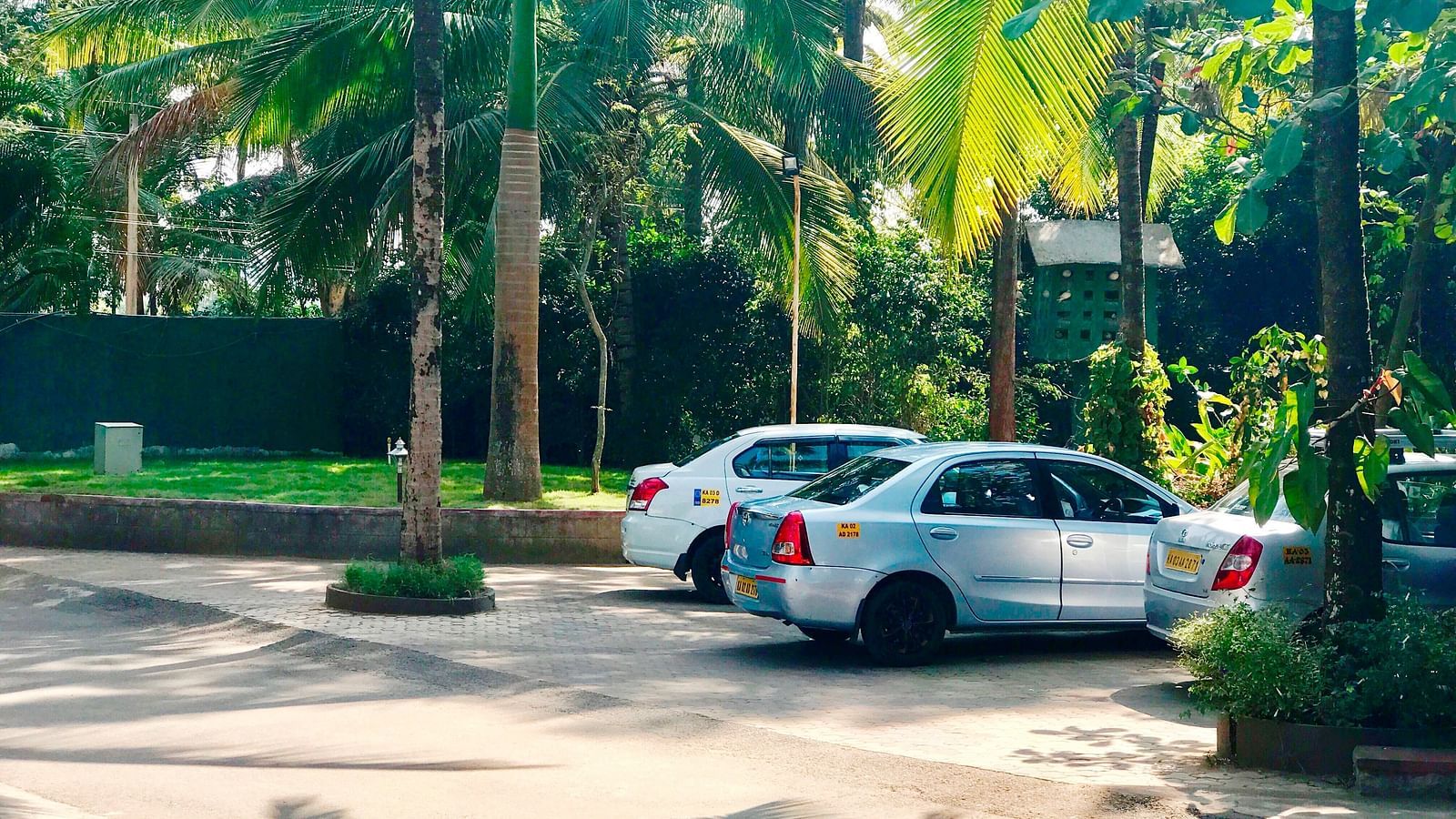 Image of an open area with two cars and trees around it at Parampara Resort & Spa, Kushalnagar.