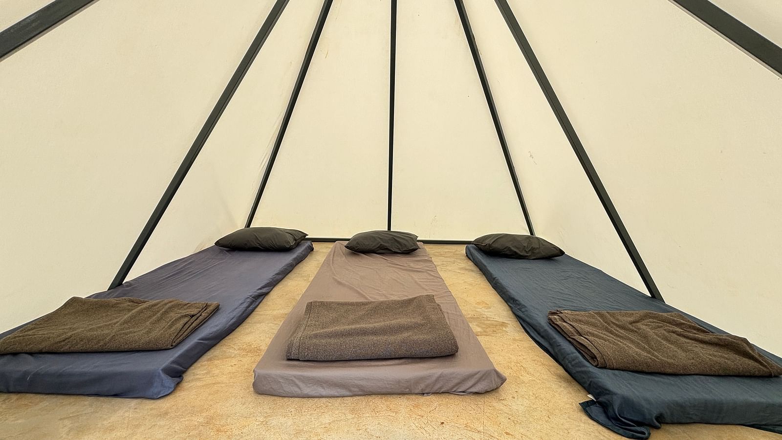 Interior of a spacious tent featuring neatly arranged sleeping mats, offering a comfortable sleeping arrangement for guests.