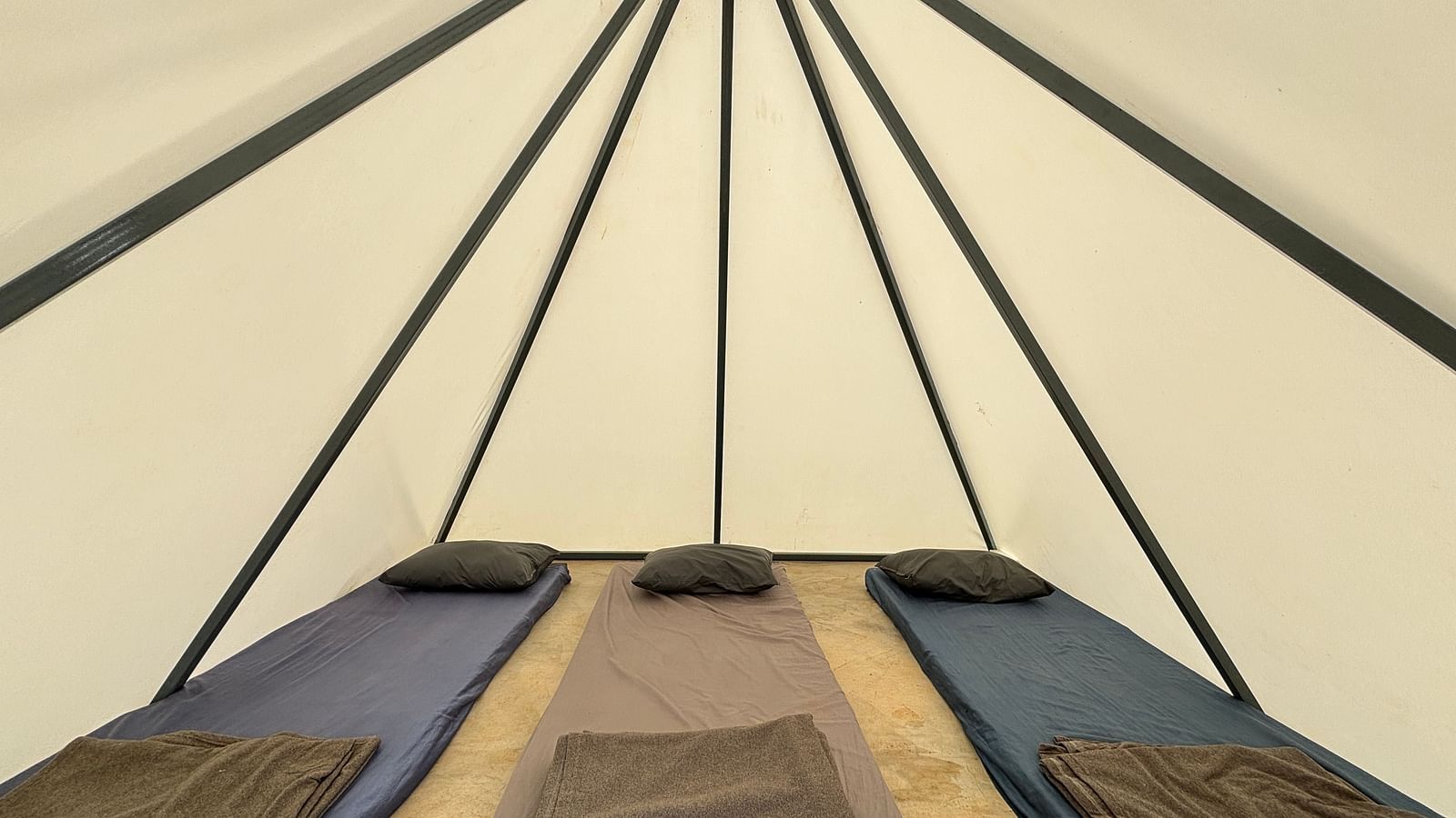 Interior of a spacious tent featuring neatly arranged sleeping mats, offering a comfortable sleeping arrangement for guests.