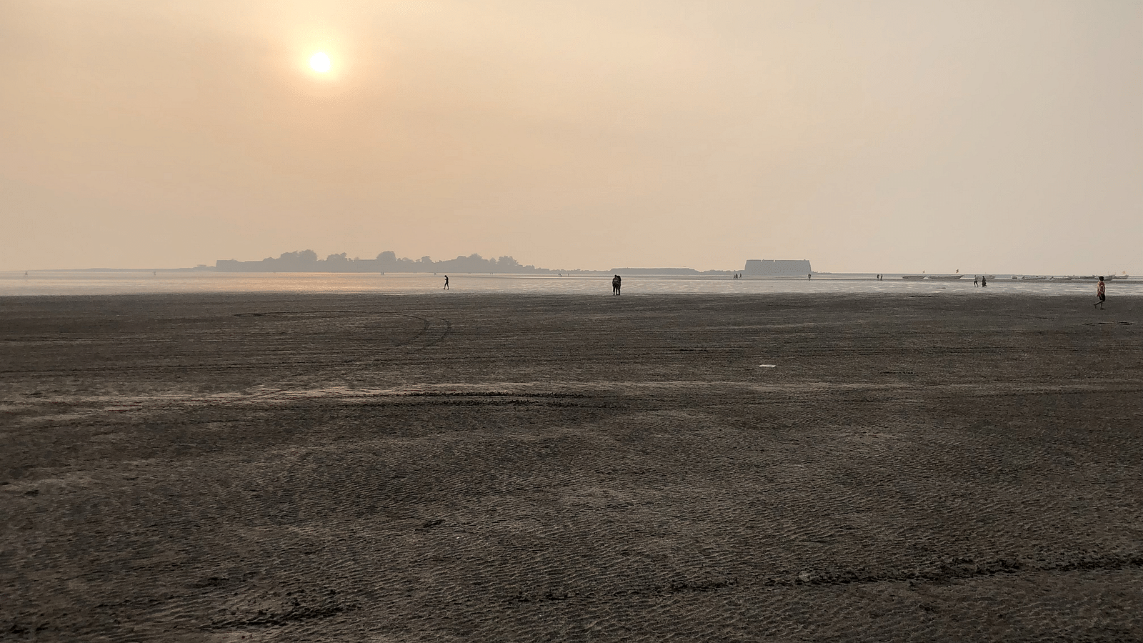 a view of a sandy beach from afar during evening