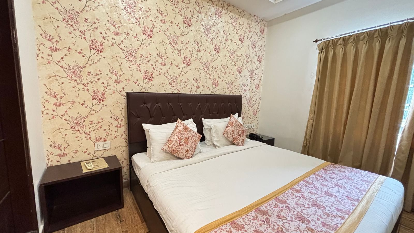 Bedroom featuring a double bed, bedside tables, and patterned wallpaper at Sumitel Premier Inn.