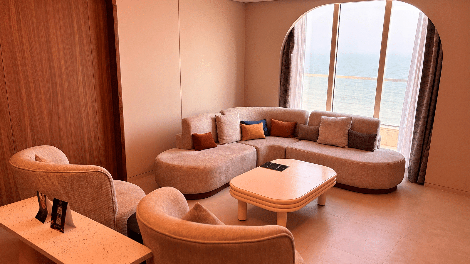 A living area at Swosti Premium Beach Resorts, Puri, with a couch, chairs, and a small table.