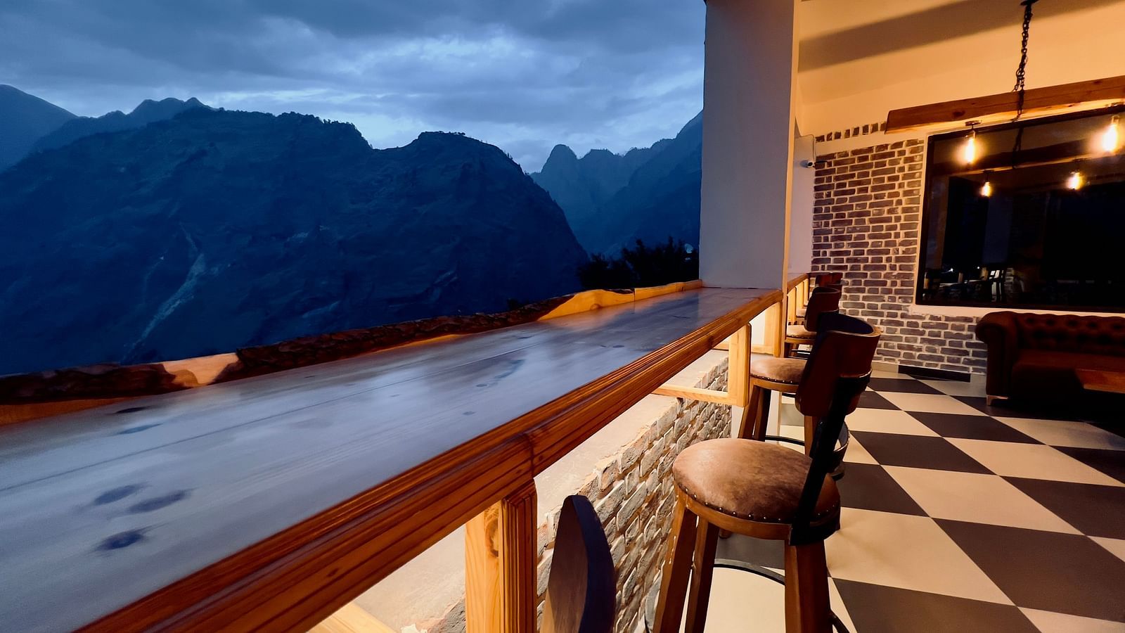 image of the bar with black and white titles and elevated chairs overlooking the beautiful mountain ranges in the background - The Tattva Boutique Resort