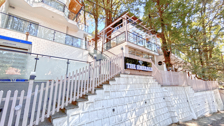 A facade image of DLS The Emerald, Nainital surrounded by tress and lush greenery