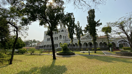 An overview of Aga Khan Palace with trees and a manicured garden in front of it.