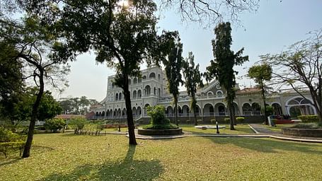 An overview of Aga Khan Palace with trees and a manicured garden in front of it.