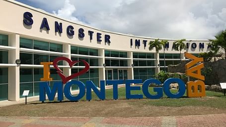 A signage of Montego Bay in front of the local airport with a walking path in front of the signage.
