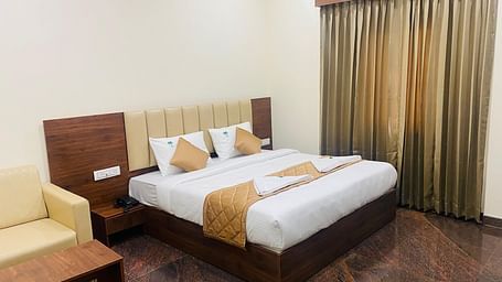 Elegant room featuring large bed, full-length curtains, and cosy ambience at Hotel Sahara Tree.