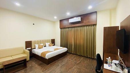 A double bed in a room area with stylish lighting, AC, rustic floor, seating and curtains at Hotel Sahara Tree.