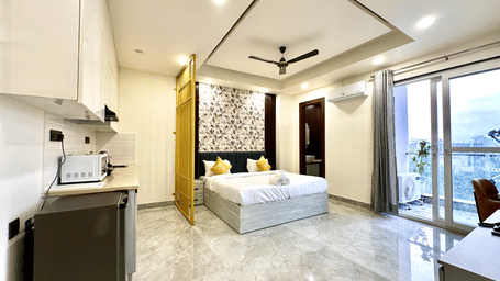 Suite of Lime Tree Hotels & Service Apartment Private Limited featuring an open kitchen, a sofa, and a glass door.
