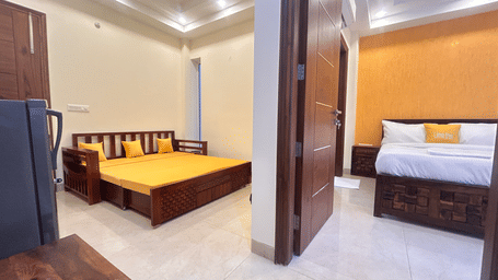 Suite of Lime Tree Hotels & Service Apartment Private Limited featuring a yellow bedspread and an adjoining bedroom visible through an open door.