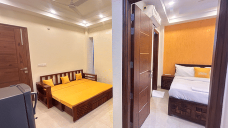 Bedroom of Lime Tree Hotels & Service Apartment Private Limited featuring a yellow bedspread and an open wardrobe door.
