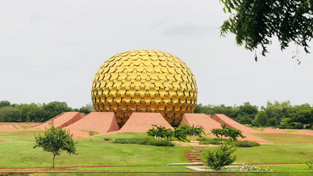 The striking, large golden geodesic dome sits amidst manicured green lawns under an overcast sky.
