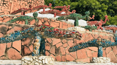 Outdoor dining area with stone walls, tables, and chairs arranged on terraced levels in a natural setting.